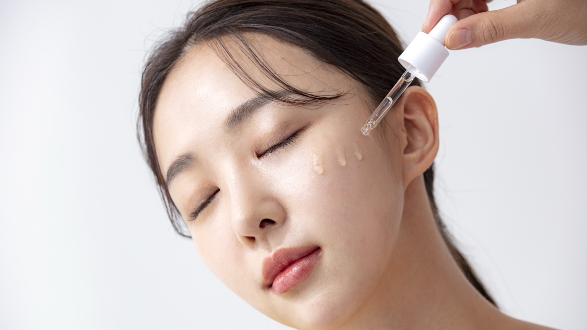 눈을 감은 여성의 볼에 스포이트로 투명한 앰플을 한 방울씩 떨어뜨리는 모습