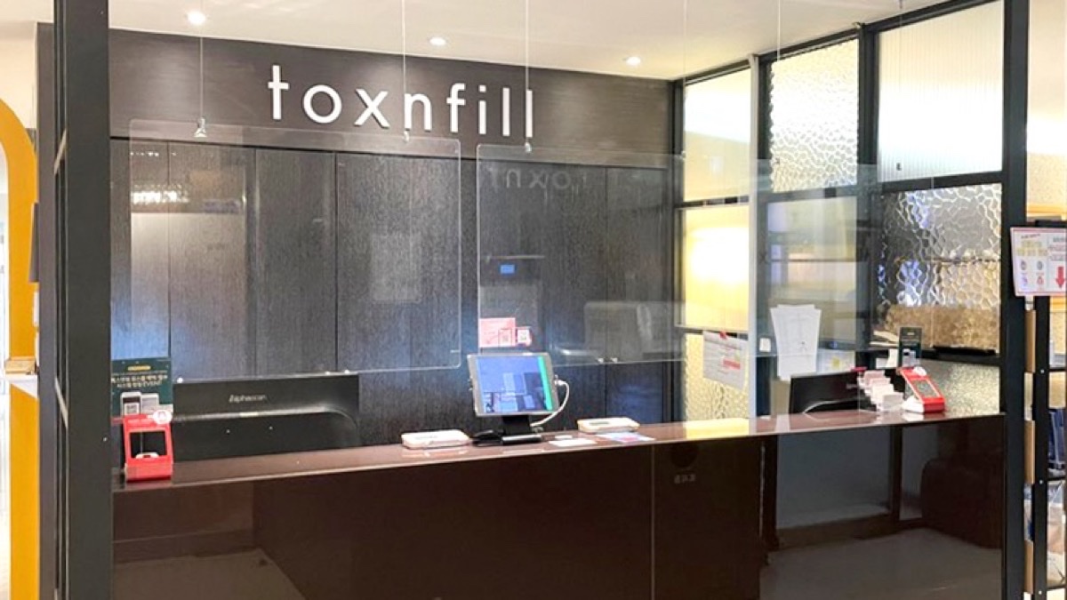 toxnfill 로고가 걸린 피부클리닉 접수 데스크와 결제 단말기