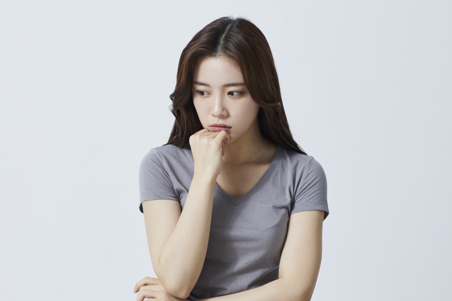 예전에 맞은 필러를 녹일지 고민하며 턱을 괴고 생각에 잠긴 여성